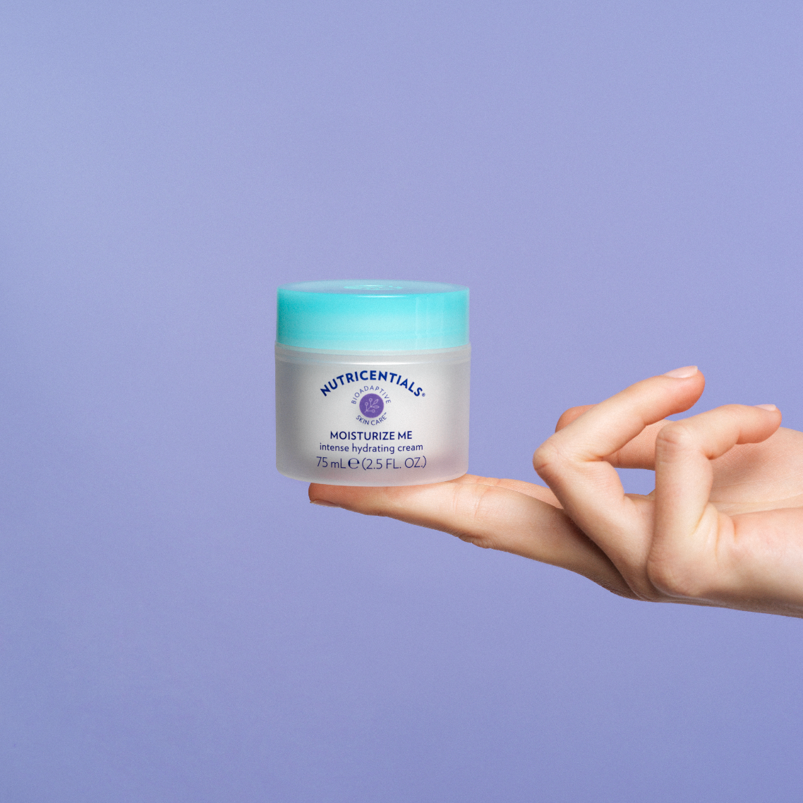 Hand balancing jar of Nutricentials Moisturize Me intense hydrating cream, 75 mL, on purple background.