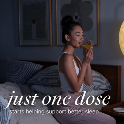 Woman sitting on a bed holding a supplement with text 'just one dose' in a bedroom setting.