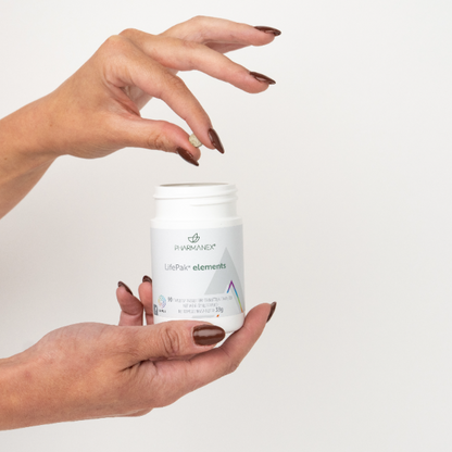 Hand holding a supplement container labeled 'LifePak elements' against a plain background