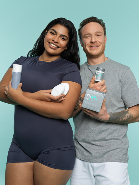 Two people holding TRME products against a teal background
