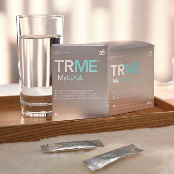 TRME MyEDGE supplement packages with a glass of water on a wooden surface.