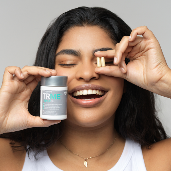 Woman holding a jar of TRME Weight Management product with a neutral background