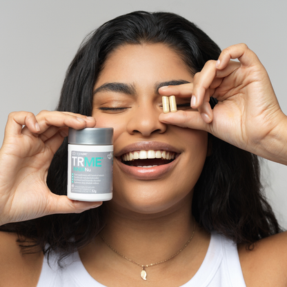Woman holding a jar of TRME Weight Management product with a neutral background