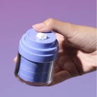 Hand holding a purple container with a white cap against a purple background