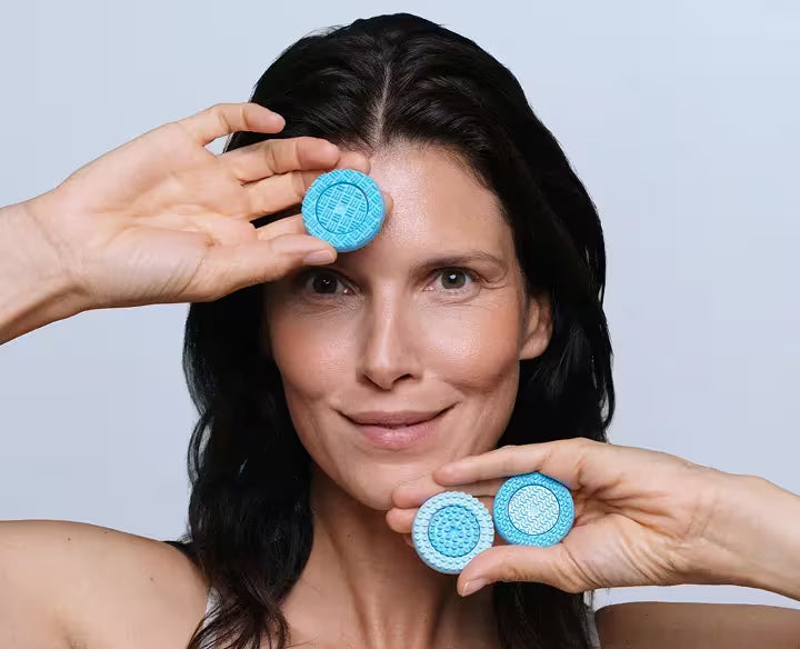 Woman holding lumispa replacement heads  against a light gray background