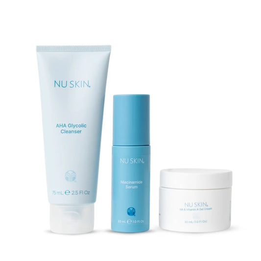 A three-piece skincare set from NU SKIN on a white background, featuring a large light blue AHA Glycolic Cleanser tube, a medium blue Meskeratin Serum bottle, and a small white jar of Oil & Serums Facial Cleanser.