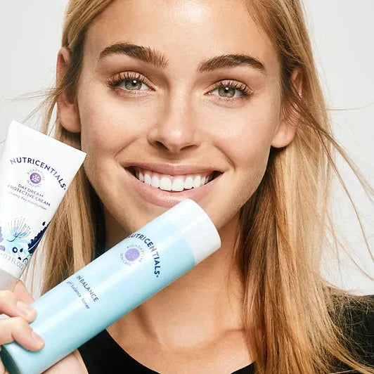 Woman holding a bottle of Nutricientals skincare product against a white background