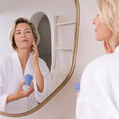 Woman applying cream to her face in front of a mirror